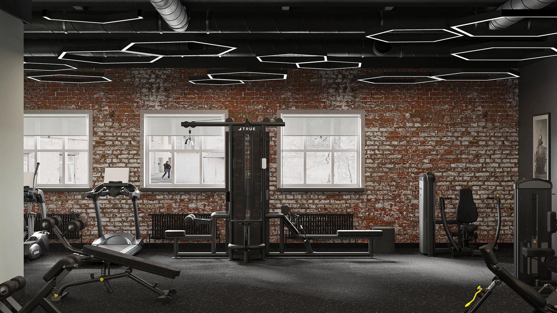 фитнес-зал с тренажёрами у кирпичной стены и большими окнами